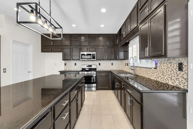 a kitchen with kitchen island granite countertop a sink a stove top oven and cabinets