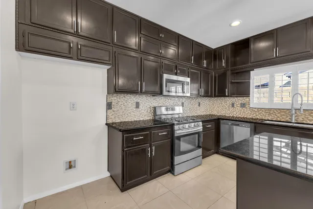 a kitchen with stainless steel appliances granite countertop a sink stove and microwave
