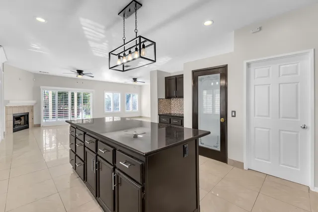 a room with stainless steel appliances granite countertop furniture a kitchen island a refrigerator and a view of living room