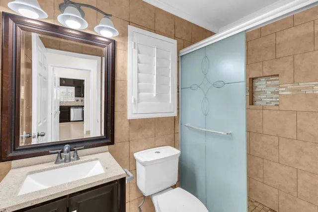 a bathroom with a sink a toilet a mirror and shower