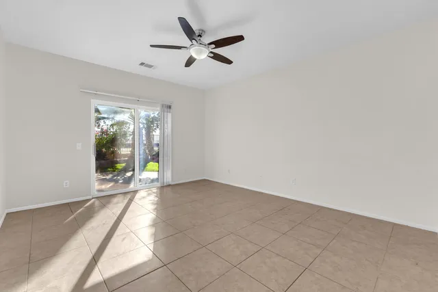 an empty room with chandelier fan and windows
