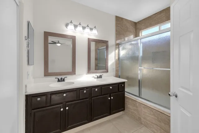 a bathroom with a double vanity sink mirror and shower