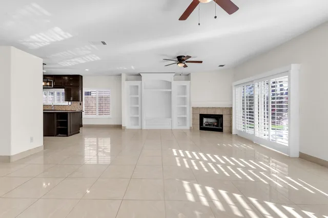 a view of a livingroom with a fireplace a chandelier and windows