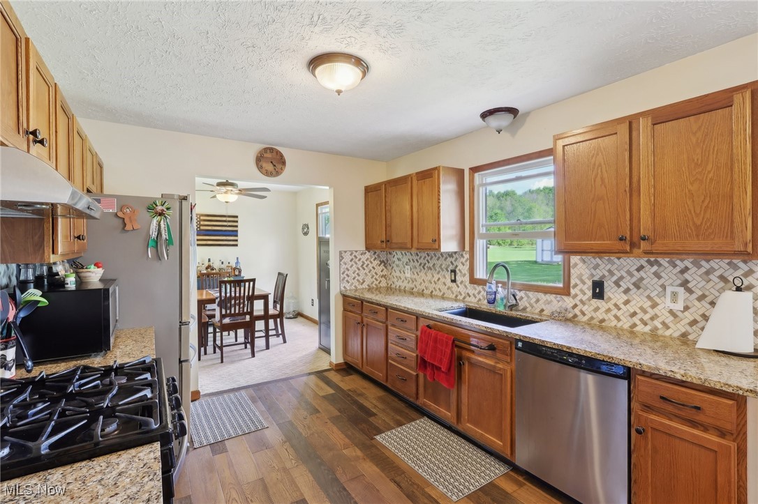 41553 Parsons Road Lagrange, OH 44050 - Photo 25 of 50 Kitchen with dishwasher, a sink, dark wood-style flooring, backsplash, and ceiling fan