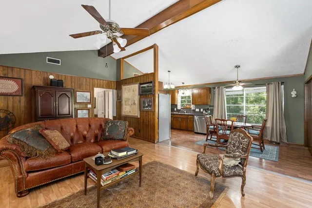 a living room with furniture a ceiling fan and a large window