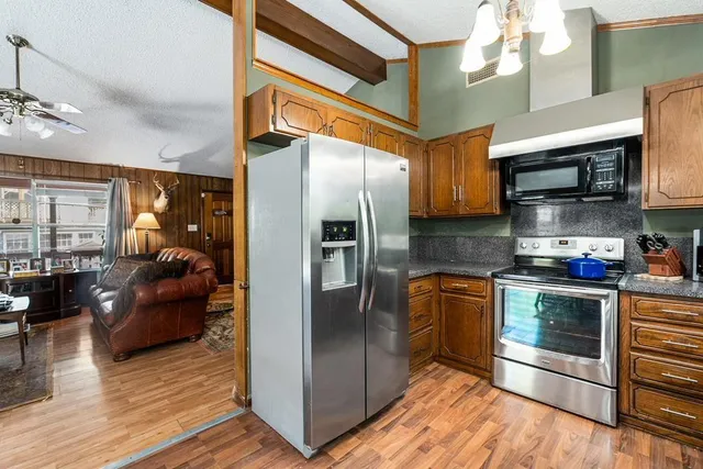 a kitchen with stainless steel appliances granite countertop a refrigerator a stove and a sink