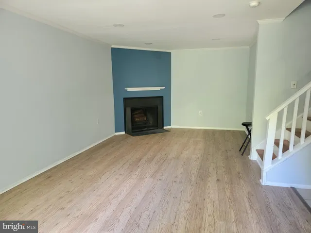 a view of an empty room with wooden floor fireplace and a window