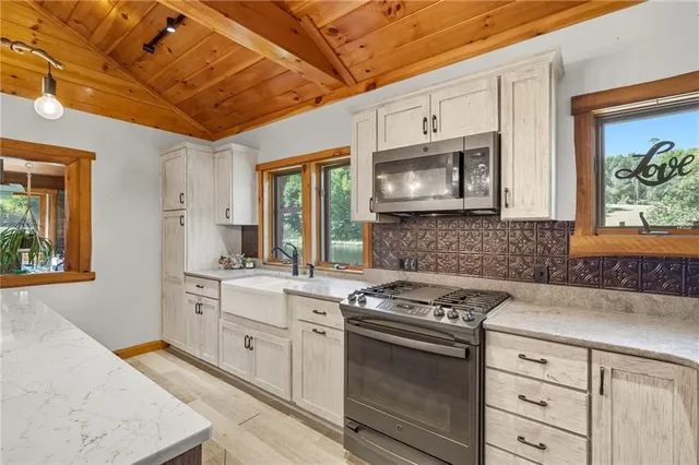 a kitchen with stainless steel appliances granite countertop a stove a sink and a microwave