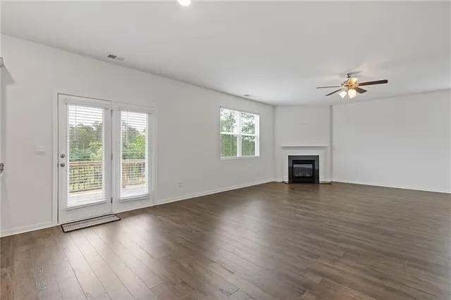 an empty room with wooden floor fan and windows