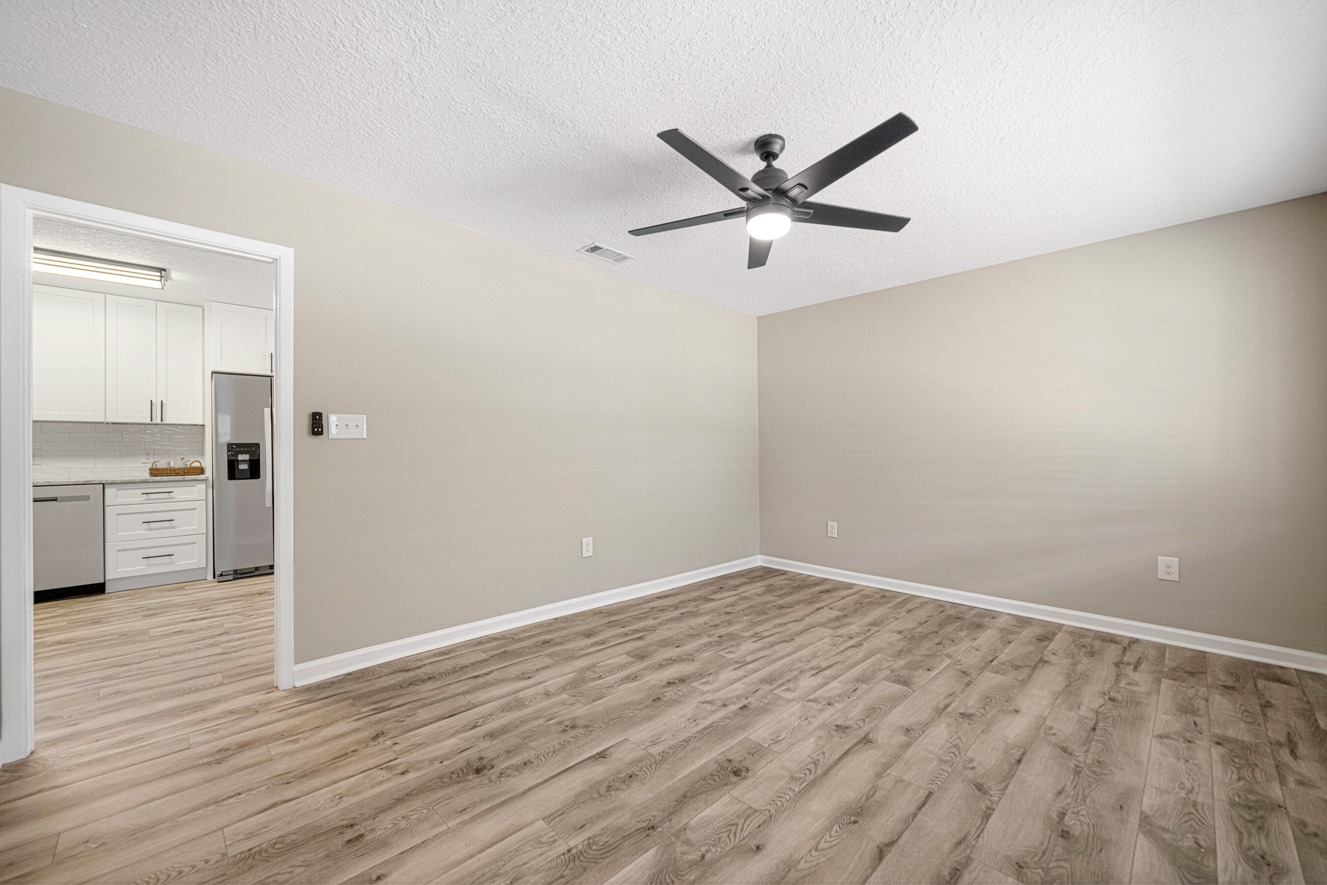 207 Oglesby Avenue Crestview, FL 32536 - Photo 13 of 30 an empty room with wooden floor a ceiling fan and windows