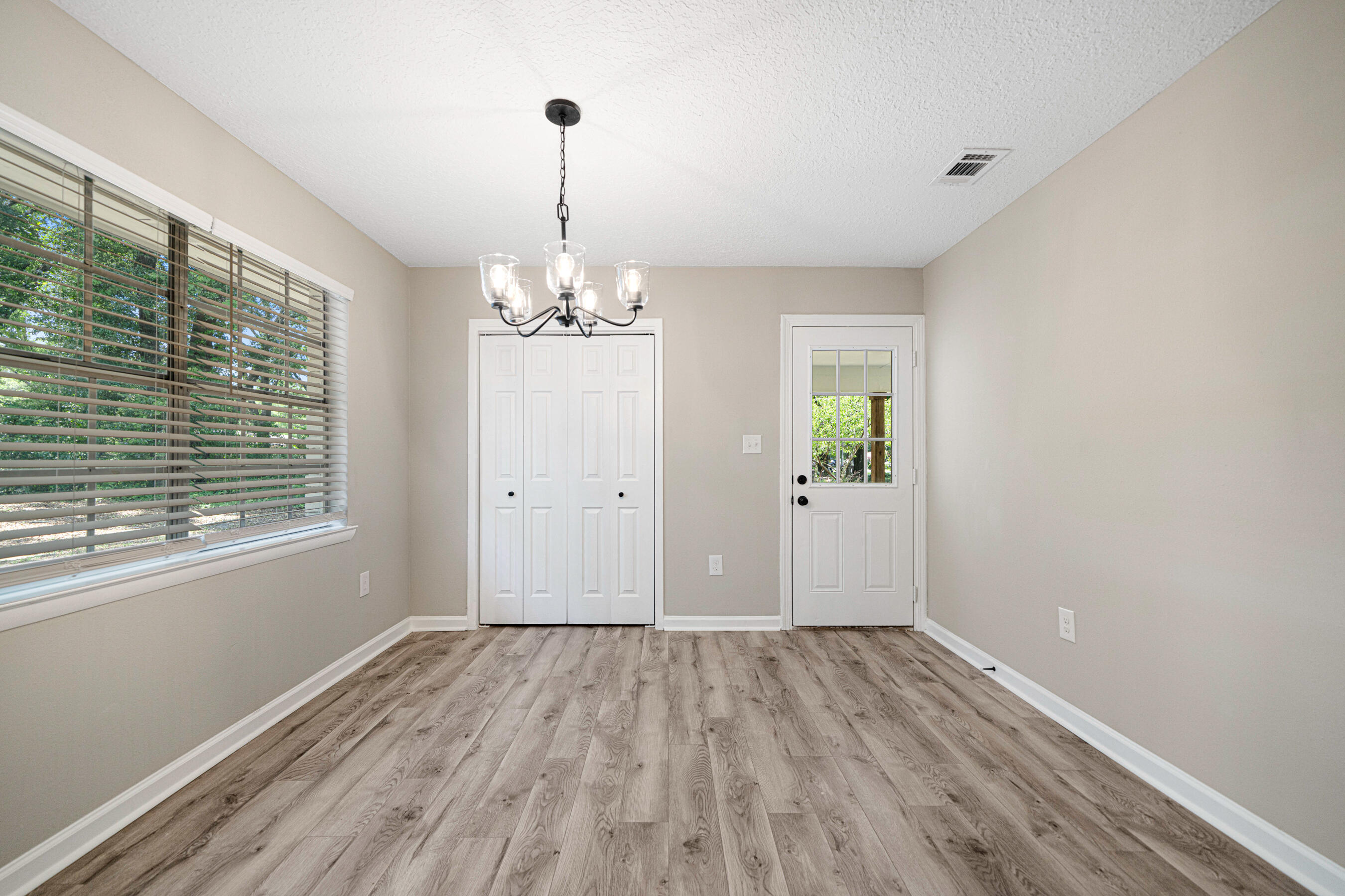 207 Oglesby Avenue Crestview, FL 32536 - Photo 10 of 30 a view of an empty room with wooden floor and a window