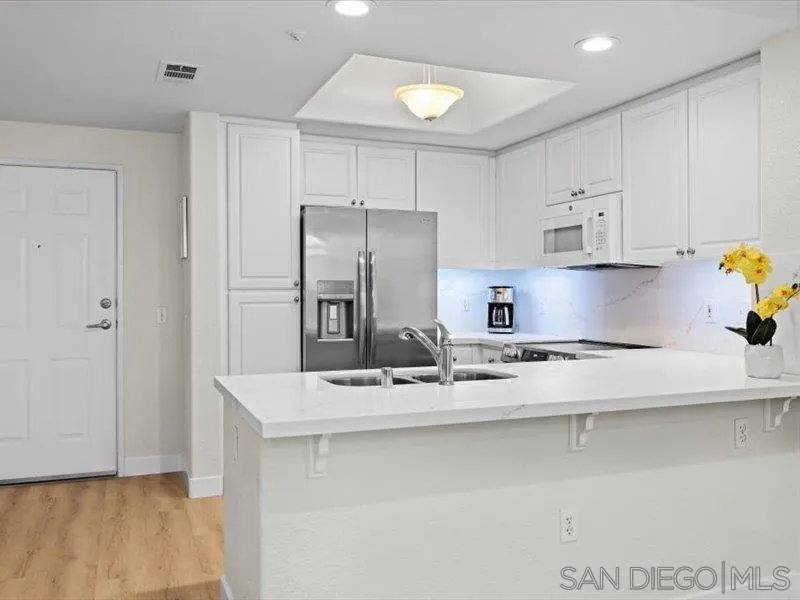 9237 Regents Road, Unit K101 La Jolla, CA 92037 - Photo 9 of 29 a kitchen with stainless steel appliances granite countertop a sink and a refrigerator