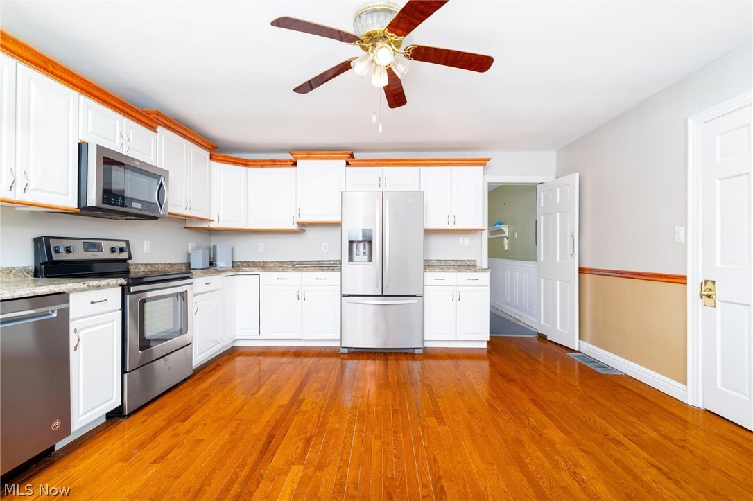 165 9th Street Wellsburg, WV 26070 - Photo 17 of 37 Kitchen with stainless steel appliances, ceiling fan, white cabinets, light wood-style flooring, and light stone countertops