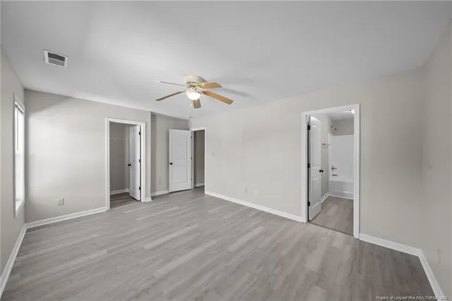 an empty room with wooden floor and ceiling fan