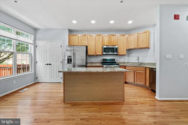a kitchen with stainless steel appliances granite countertop a refrigerator and a stove top oven