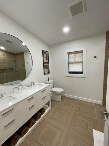 a spacious bathroom with a double vanity sink mirror and toilet