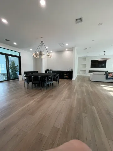 a view of a livingroom with furniture wooden floor fireplace and windows