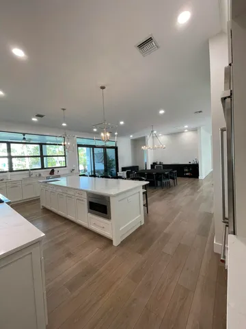 a large white kitchen with a large counter top and stainless steel appliances