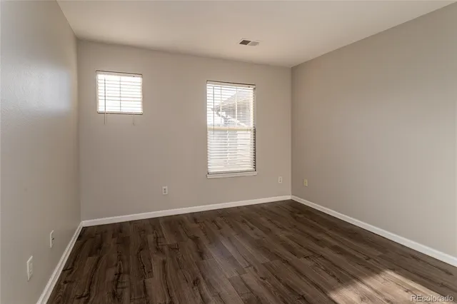 a view of an empty room with wooden floor and window