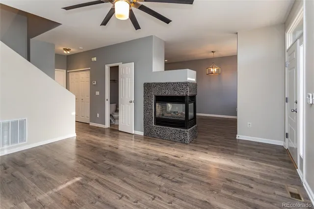 an empty room with wooden floor fireplace and windows