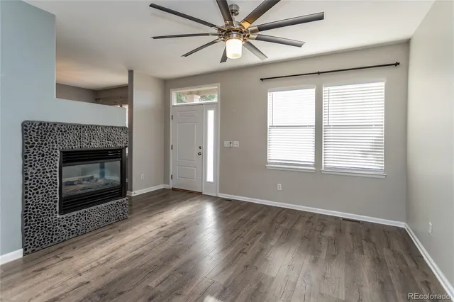 a view of an empty room with wooden floor fireplace and a window