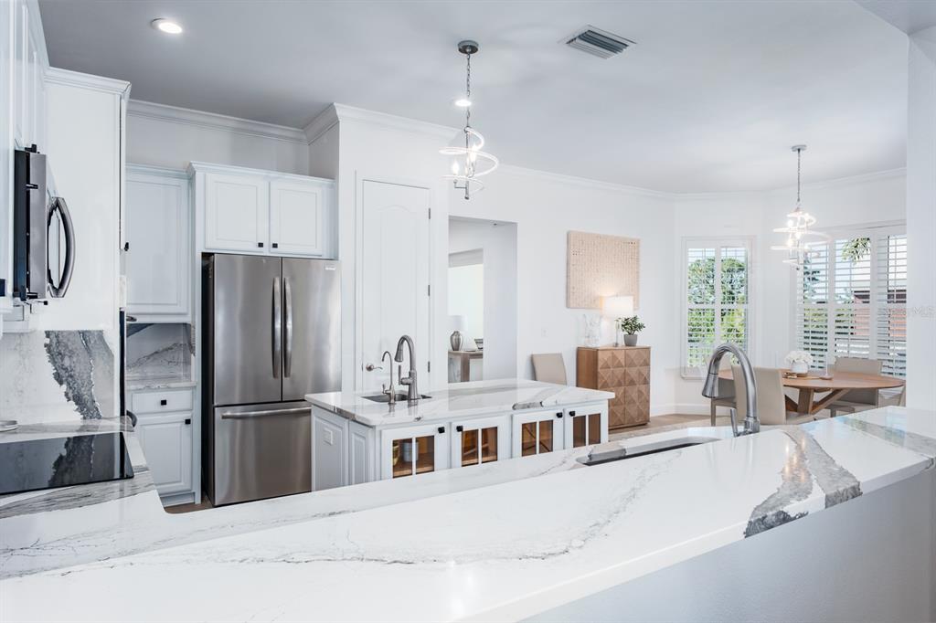 1700 Oyster Point Way Palm Harbor, FL 34683 - Photo 22 of 88 a kitchen with stainless steel appliances kitchen island granite countertop a refrigerator a sink dishwasher a oven with white cabinets and wooden floor