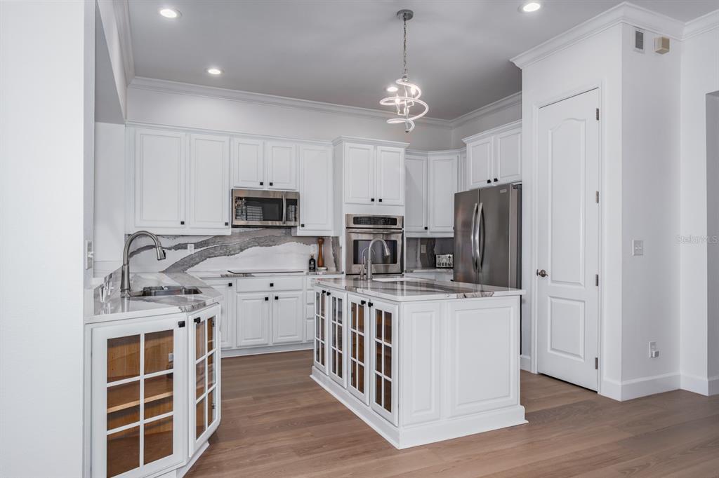 1700 Oyster Point Way Palm Harbor, FL 34683 - Photo 23 of 88 a kitchen with stainless steel appliances granite countertop a stove top oven a refrigerator a sink and dishwasher with wooden floor