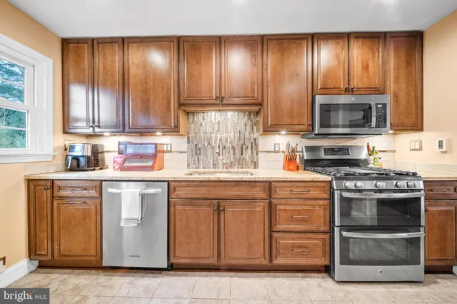a kitchen with stainless steel appliances granite countertop a stove a sink and a refrigerator