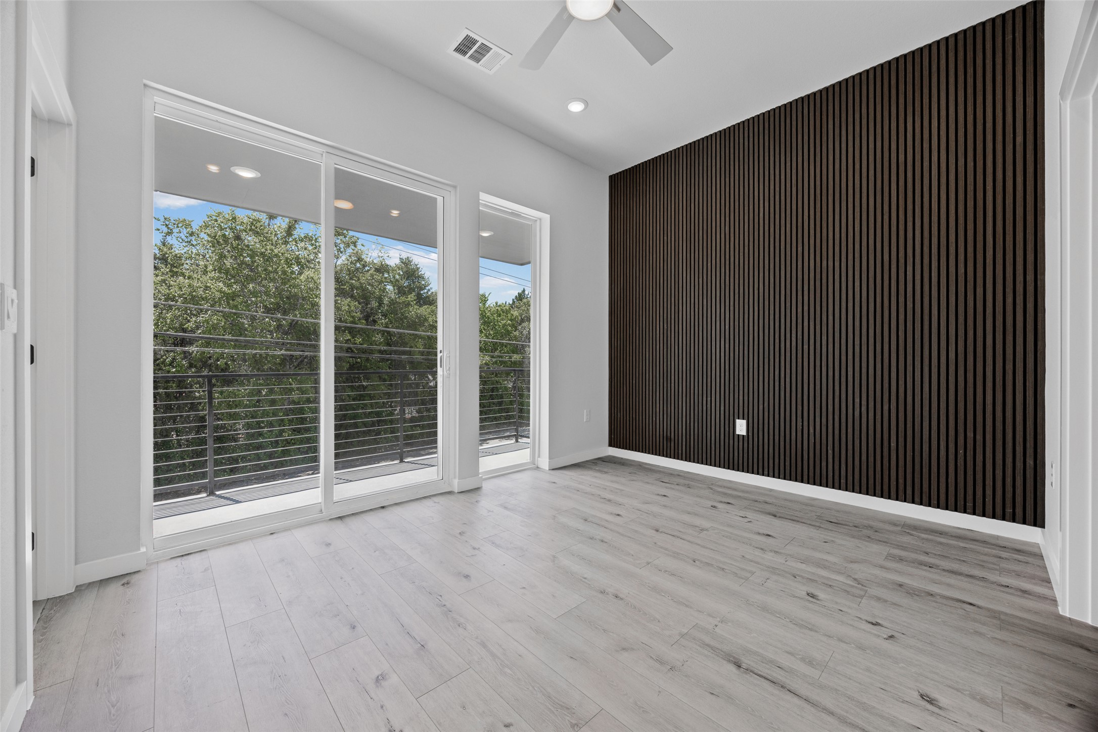 2000 Riverside Farms Road, Unit 5102 Austin, TX 78741 - Photo 14 of 25 A spacious room features light-toned flooring, a distinctive accent wall, and expansive glass doors opening to a balcony.