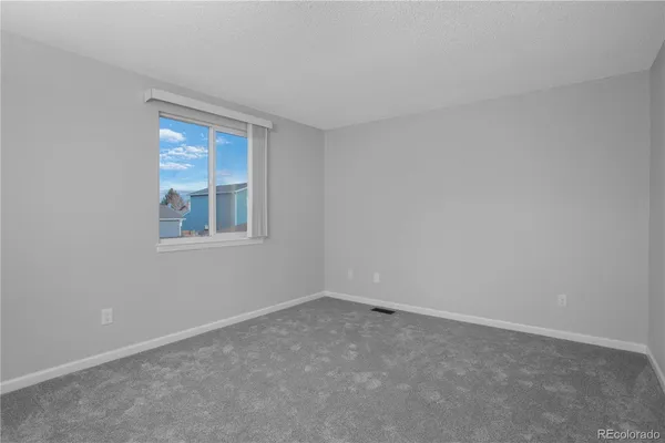 a view of an empty room with closet and a window