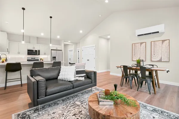 a living room with furniture kitchen view and a wooden floor