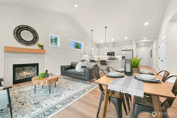 a living room with furniture a fireplace and a dining table with wooden floor