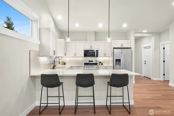 a kitchen with stainless steel appliances kitchen island granite countertop a dining table chairs and white cabinets