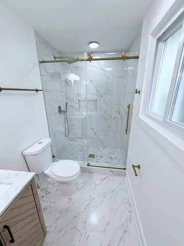 a bathroom with a granite countertop sink toilet and shower