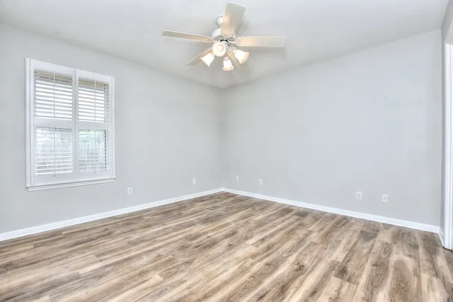 an empty room with wooden floor closet and windows
