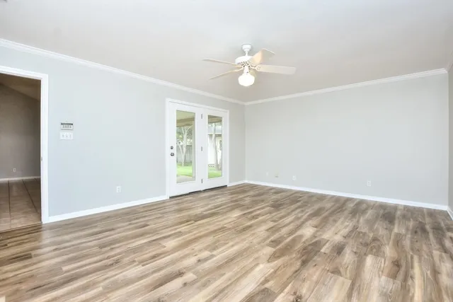 a view of an empty room with wooden floor and a window