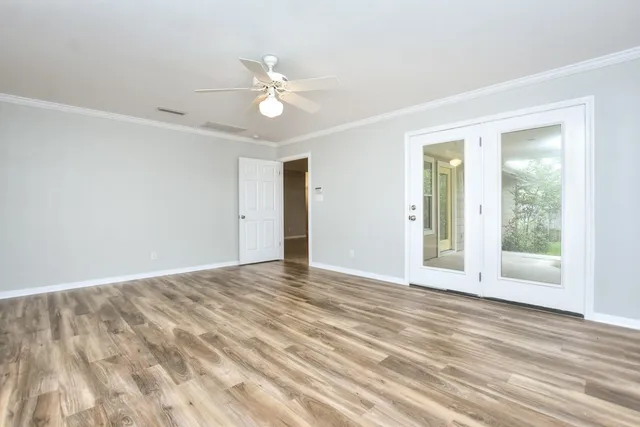an empty room with wooden floor and ceiling fan