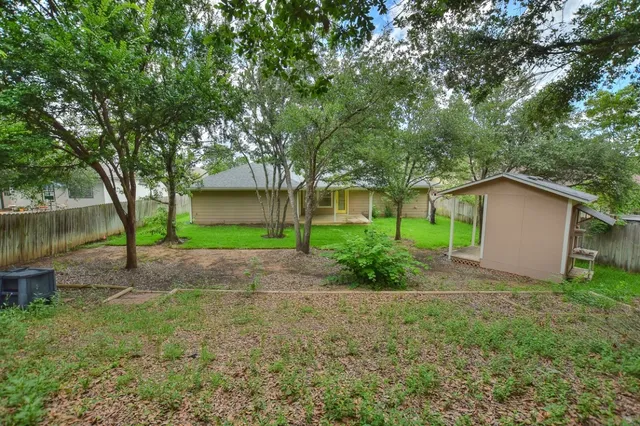 a view of a house with a yard and large tree
