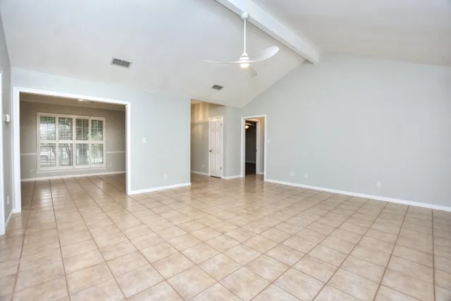a view of an empty room with window and chandelier fan