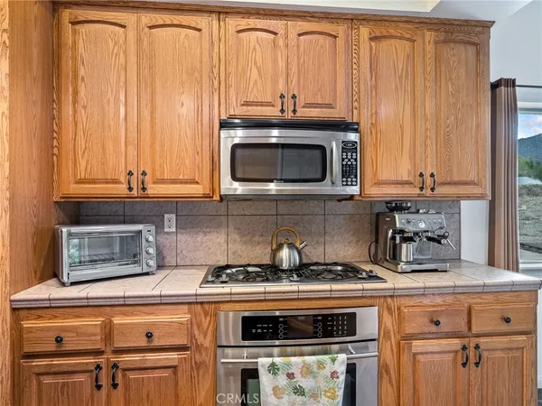 a kitchen with granite countertop a stove a microwave and wooden cabinets