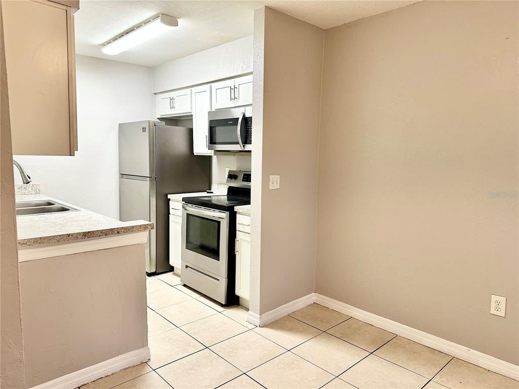 5801 Windhover Drive, Unit A01 Orlando, FL 32819 - Photo 4 of 14 a kitchen with stainless steel appliances a refrigerator sink and cabinets