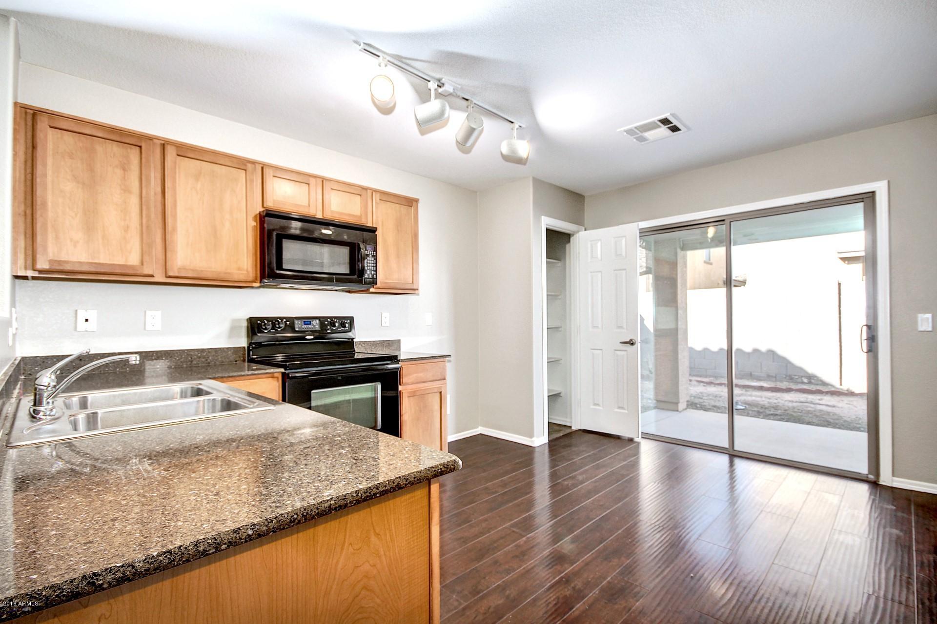 6416 West Beverly Road Laveen, AZ 85339 - Photo 2 of 22 a kitchen with granite countertop a stove top oven a sink a counter space and cabinets