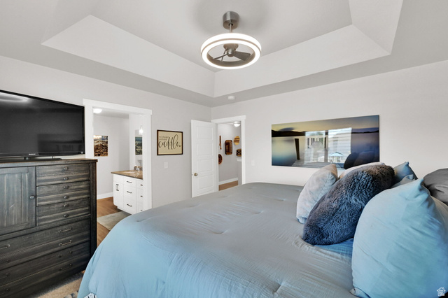 2777 West 4175th Street South, Unit 232 Roy, UT 84067 - Photo 19 of 27 Primary Bedroom- featuring primary en suite, walk in closet, window with plantation shutters, ceiling fan with integrated lighting, carpet, and light-toned wall paint