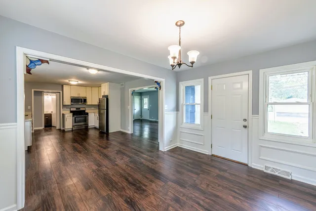a view of a livingroom with wooden floor staircase and kitchen view