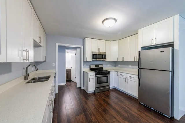 a kitchen with cabinets wooden floor and stainless steel appliances