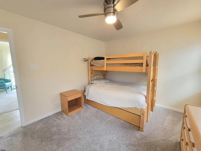 a bedroom with a bed a chair and potted plant on the dresser