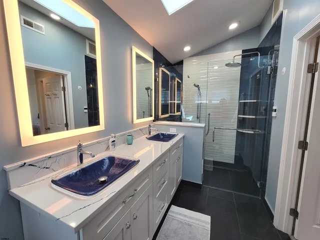 a bathroom with a double vanity sink a mirror and a shower