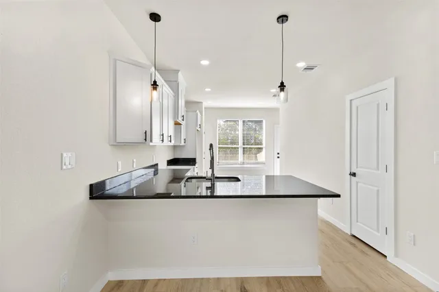 a kitchen with granite countertop white cabinets and window