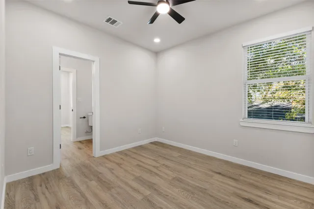 an empty room with wooden floor cabinet and windows