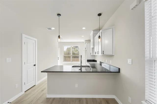 a large kitchen with granite countertop a sink a counter top space and cabinets